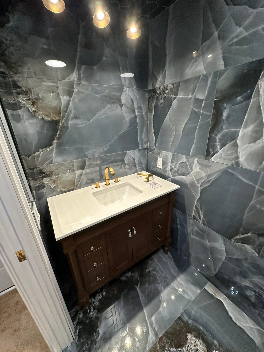 Dark marble bathroom with gold fixtures and wood vanity by NoBull Man