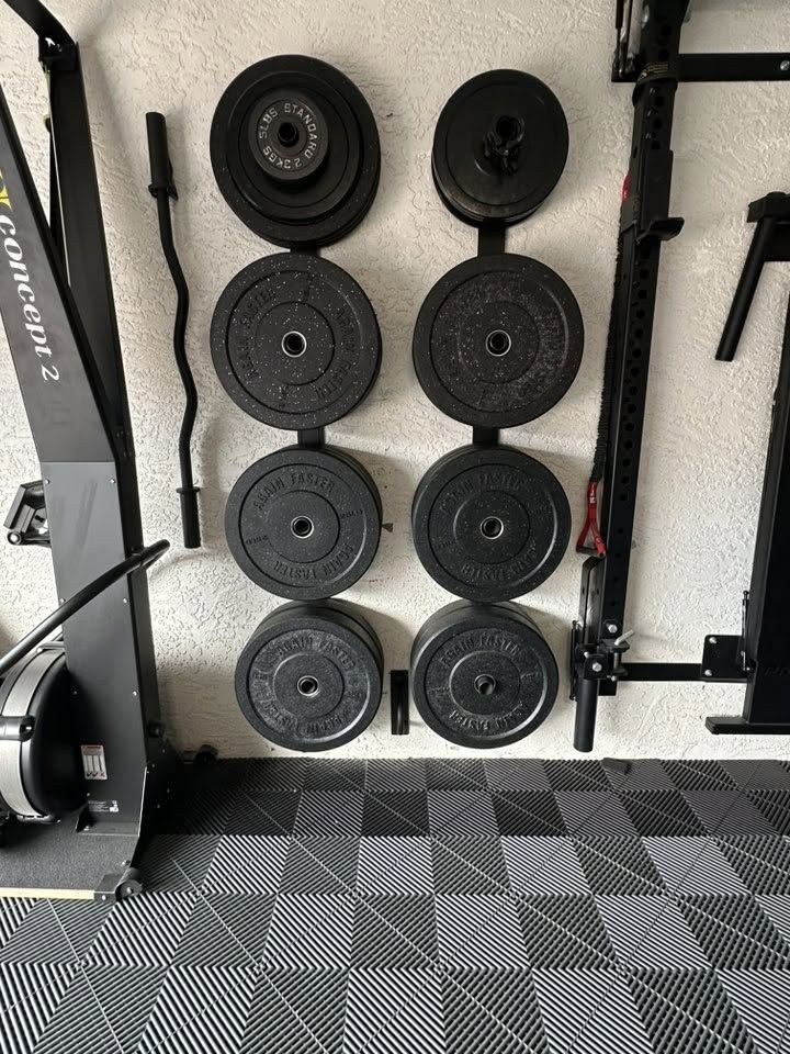 Custom home gym built by NoBull Man — wall-mounted weight plates, rubber flooring and full equipment